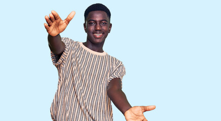 Young african american man wearing casual clothes looking at the camera smiling with open arms for hug. cheerful expression embracing happiness.