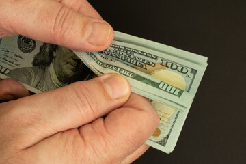 Hands counting American dollar bills on a black background