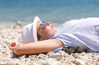 Young slim beautiful girl with sunglasses and white hat relaxing on sunset beach, summer vacation, sunny
