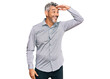 © Krakenimages.com - Middle age grey-haired man wearing casual clothes very happy and smiling looking far away with hand over head. searching concept.