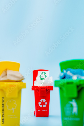 Yellow, green and red recycle bins with recycle symbol on blue background. Keep city tidy, Leaves the recycling symbol. Nature protection concept