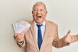 Senior caucasian man holding swedish krona banknotes celebrating achievement with happy smile and winner expression with raised hand