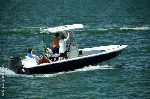 Cuadros en Lienzo Three men and a woman enjoying a leisurely morning cruise on the Florida Intra-Coastal Waterway in an open sport fishing boat powered by a single outboard engine