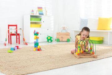 Poster - Cute little girl playing with bead maze on floor at home, space for text. Educational toy