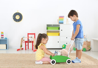 Sticker - Cute little children playing with toy walker at home