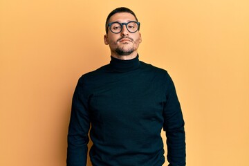 Poster - Handsome man with tattoos wearing turtleneck sweater and glasses looking sleepy and tired, exhausted for fatigue and hangover, lazy eyes in the morning.