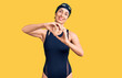 © Krakenimages.com - Young beautiful hispanic woman wearing swimwear and swimmer glasses smiling in love doing heart symbol shape with hands. romantic concept.