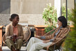 © Seventyfour - Portrait of two contemporary young women enjoying wine while relaxing in lounge chairs at outdoor terrace, copy space
