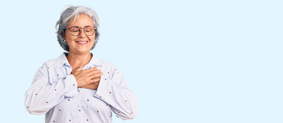 Wall Mural - Senior woman with gray hair wearing casual business clothes and glasses smiling with hands on chest with closed eyes and grateful gesture on face. health concept.