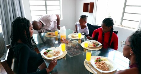 Wall Mural - Black African family sitting down at lunch table to eat meal