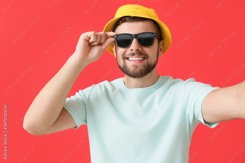 Handsome man with stylish sunglasses taking selfie on color background - obrazy, fototapety, plakaty 