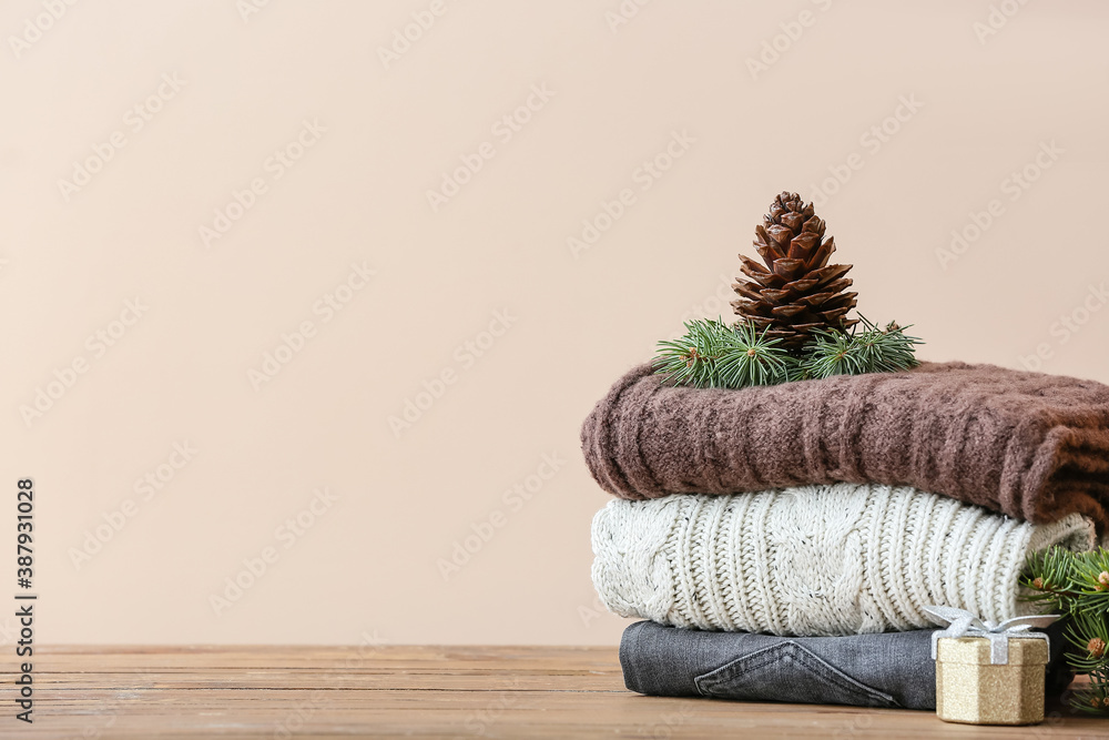 Stylish Christmas clothes on table against color background