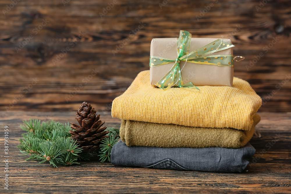 Stylish Christmas clothes with gift on table