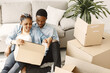 © prostooleh - Young couple moving in to new home together. African american couple with cardboard boxes.