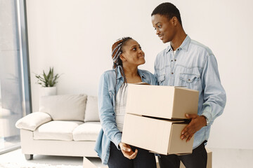 Wall Mural - Young couple moving in to new home together. African american couple with cardboard boxes.