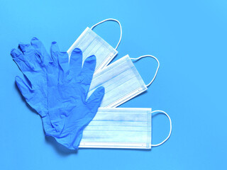 Medical protective masks and latex gloves on a blue background. Individual, disposable hygiene equipment. Quarantine healthcare, hygiene and coronavirus protection concept.