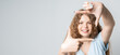 © AstiMak - Photo of funny woman smiling and making photo frame with fingers. Human emotions, facial expression concept. Copy space