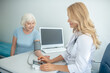 © zinkevych - Female cardiologist measuring blood-pressure to good-looking elderly woman