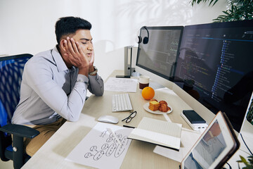 Wall Mural - tired young indian programmer almost sleeping at his desk after working on difficult project all day