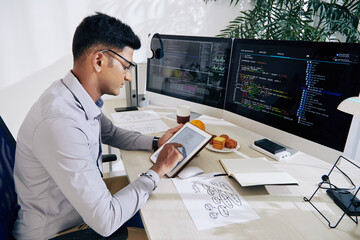 Wall Mural - serious young indian software developer checking mindmap on tablet computer when planning work on pr