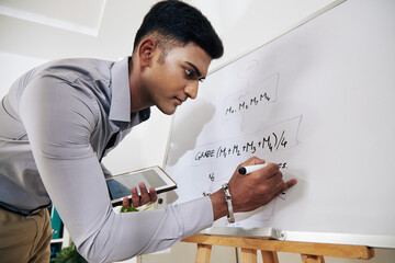 Wall Mural - serious young indian software engineer drawing block diagram on whiteboard