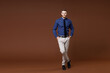 © ViDi Studio - Full length of smiling confident young business man in blue shirt tie holding hands in pockets looking camera isolated on brown background studio portrait. Achievement career wealth business concept.