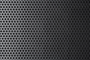 Industrial background. Black metal surface with regular round holes as texture (abstract)