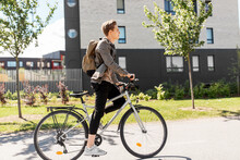 Lifestyle, Transport And People Concept - Young Man Or Teenage Student Boy With Backpack Riding Bicycle On City Street