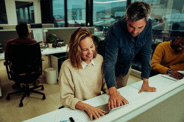 Caucasian business partners working on collaboration design project researching on laptop standing in office block