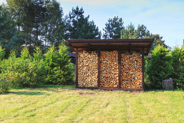 Firewood harvested for heating in winter. A pile of firewood in the courtyard of the house on the green grass