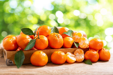 Wall Mural - Fresh mandarin oranges fruit or tangerines with leaves over green blurred background