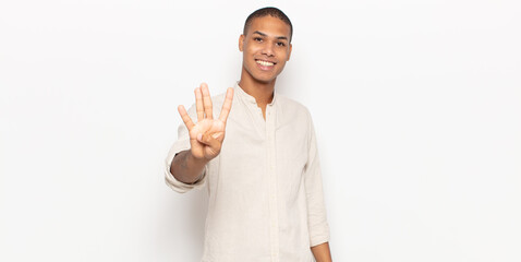 Wall Mural - young black man smiling and looking friendly, showing number four or fourth with hand forward, counting down