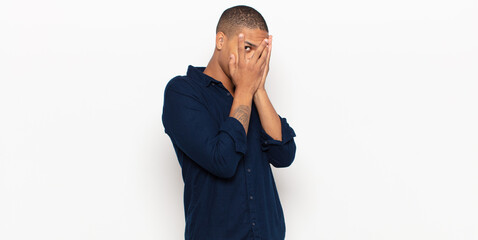 Wall Mural - young black man feeling scared or embarrassed, peeking or spying with eyes half-covered with hands