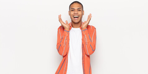 Wall Mural - young black man feeling shocked and excited, laughing, amazed and happy because of an unexpected surprise