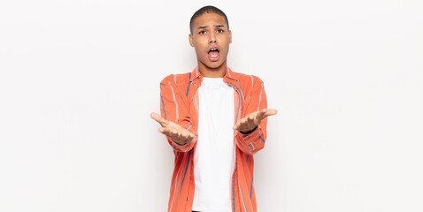 Wall Mural - young black man feeling extremely shocked and surprised, anxious and panicking, with a stressed and horrified look