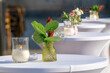 Outdoor cafeteria with white chairs and tables with decorative flowers in vases and candles