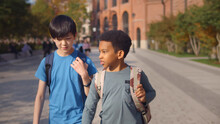 Two Diverse School Kids Walking Home Together After School And Talking