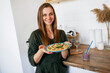 © Denys - A young girl with a wide smile in the kitchen is holding a vegetarian pizza.