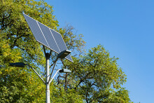 Alternative Solar Energy. Solar Device With Street Lamp On Background Of Blue Sky And Green Tree. Street Light Powered By Solar Panel With Battery Included. Copy Space