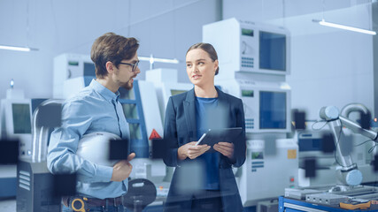Aufkleber - Modern Factory: Female Project Manager and Male Engineer Standing, Talking, Using Digital Tablet for Programming and Monitoring Assembly Line. Industry 4.0 Facility with High Tech Machinery