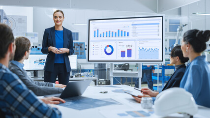 Poster - Modern Industrial Factory Meeting: Confident Female Engineer Uses Interactive Whiteboard, Makes Report to a Group of Engineers, Managers Talks and Shows Statistics, Growth and Analysis Information