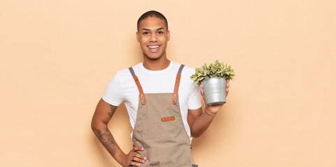 Sticker - young black man smiling happily with a hand on hip and confident, positive, proud and friendly attitude