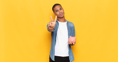 Sticker - young black man smiling and looking happy, carefree and positive, gesturing victory or peace with one hand