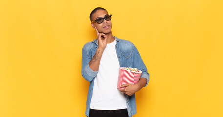 Wall Mural - young black man smiling happily and daydreaming or doubting, looking to the side