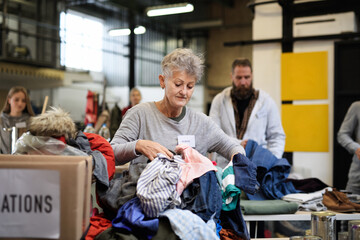 Volunteers sorting out donated clothes in community charity donation center.