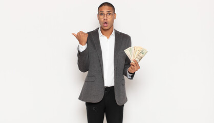 Wall Mural - young black man looking astonished in disbelief, pointing at object on the side and saying wow, unbelievable