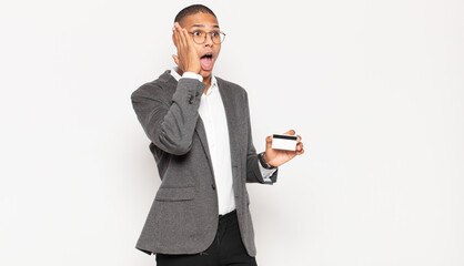 Sticker - young black man feeling happy, excited and surprised, looking to the side with both hands on face