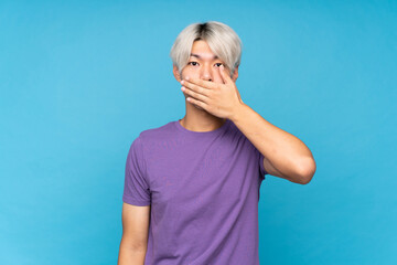 Wall Mural - Young asian man over isolated blue background covering mouth with hands