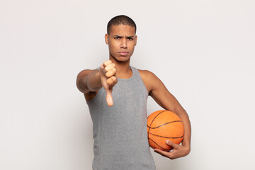 Wall Mural - young black man feeling cross, angry, annoyed, disappointed or displeased, showing thumbs down with a serious look