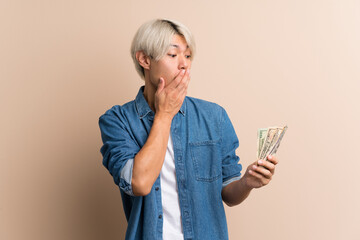 Wall Mural - Young asian man over isolated background taking a lot of money